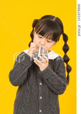 Asian little girl holds a glass of water, promoting hydration, healthy drinking habit, child lifestyle concept Asian little girl holds a glass of water, promoting hydration, healthy drinking habit, child lifestyle concept 141879666
