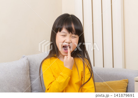 Asian girl pointing to open mouth with tooth pain, child showing dental problem at home, healthcare concept 141879691