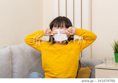 Asian girl blowing nose with tissue sick child flu cold healthcare concept Asian girl blowing nose with tissue sick child flu cold healthcare concept 141879700