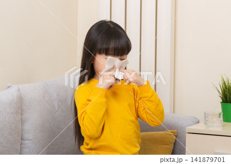 Asian girl blowing nose with tissue sick child flu cold healthcare concept Asian girl blowing nose with tissue sick child flu cold healthcare concept 141879701