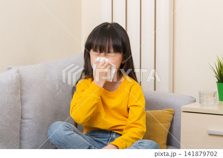 Asian girl blowing nose with tissue sick child flu cold healthcare concept Asian girl blowing nose with tissue sick child flu cold healthcare concept 141879702
