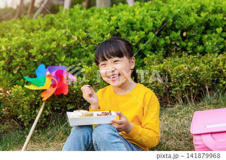 Asian little girl eating dessert in park, smiling happily, outdoor childhood lifestyle for leisure, picnic and healthy growth concept Asian little girl eating dessert in park, smiling happily, outdoor childhood lifestyle for leisure, picnic and healthy growth concept 141879968