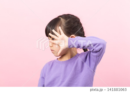 Little girl covering her face with an arm and reaching out a hand to say stop. Little girl covering her face with an arm and reaching out a hand to say stop. 141881063