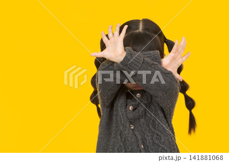 Defensive little girl covering her face with crossed hands to protect her privacy. Defensive little girl covering her face with crossed hands to protect her privacy. 141881068
