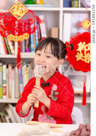Smiling Asian Child Holding Traditional Rice Crust Snacks for Spring Festival,The text on the pendant hanging at the back reads: "Happy New Year." Smiling Asian Child Holding Traditional Rice Crust Snacks for Spring Festival,The text on the pendant hanging at the back reads: "Happy New Year." 141881250