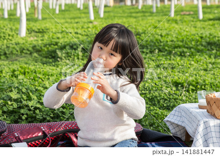 Active little girl drinking water from bottle after playing in the park, hydration concept. Active little girl drinking water from bottle after playing in the park, hydration concept. 141881447