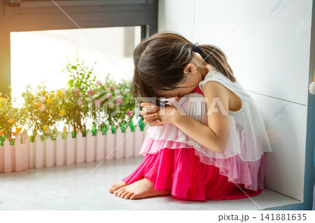 Sad and lonely little girl sitting on the floor in the corner looking depressed Sad and lonely little girl sitting on the floor in the corner looking depressed 141881635