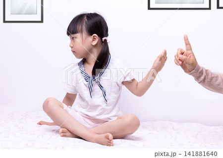 Rebellious little girl gesturing no and ignoring adult pointing finger at home 141881640