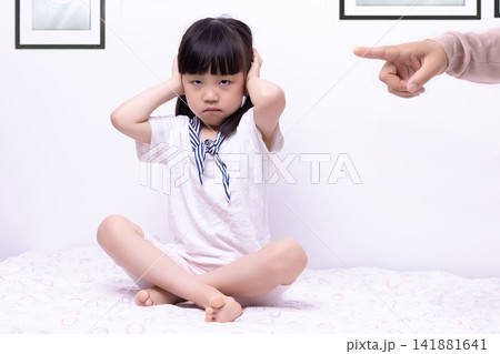 Rebellious little girl gesturing no and ignoring adult pointing finger at home 141881641