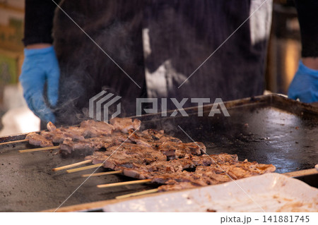 鉄板の上で湯気と煙を上げながら香ばしく焼かれる串焼き肉 鉄板の上で湯気と煙を上げながら香ばしく焼かれる串焼き肉 141881745