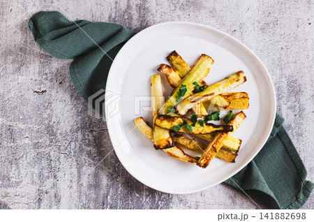 Close up of appetizing baked zucchini strips on a plate and a bowl of sauce on the table top view 141882698