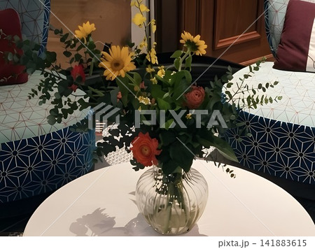 モダンなラウンジのテーブルに飾られた黄色とオレンジの花束とガラス花瓶 141883615