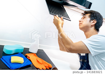 Asian male worker removing range cooker hood filter looking inside 141883821
