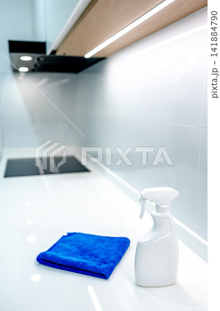 Detergent spray bottle and blue microfiber cloth on white countertop in the kitchen Detergent spray bottle and blue microfiber cloth on white countertop in the kitchen 141884790