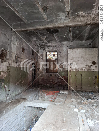 Creepy atmosphere inside an abandoned brick building with concrete floors and a barred window Creepy atmosphere inside an abandoned brick building with concrete floors and a barred window 141884808