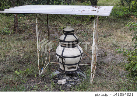 Portable ceramic tandoor oven under canopy in garden for cooking and food preparation Portable ceramic tandoor oven under canopy in garden for cooking and food preparation 141884821