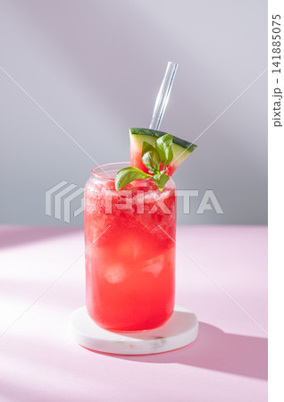 A watermelon lemonade or mojito with ice and basil in a glass on a pink gray background A watermelon lemonade or mojito with ice and basil in a glass on a pink gray background 141885075
