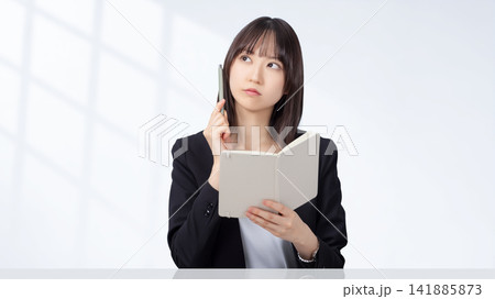 ペンと手帳を持って考える女性・ビジネスウーマン ペンと手帳を持って考える女性・ビジネスウーマン 141885873