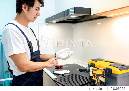 Asian male maintenance worker putting on protective gloves in the kitchen 141886051