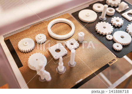 White 3d printed gears and small parts arranged on a printer bed during prototyping and mechanical testing. White 3d printed gears and small parts arranged on a printer bed during prototyping and mechanical testing. 141886718