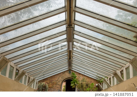 Glass Greenhouse Roof with Hanging Plants and Historic Brick Structure Glass Greenhouse Roof with Hanging Plants and Historic Brick Structure 141887051