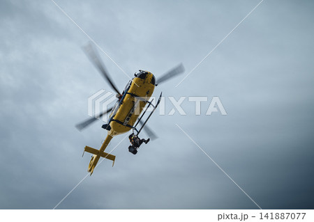 Paramedics hanging on rope under flying helicopter emergency medical service Paramedics hanging on rope under flying helicopter emergency medical service 141887077
