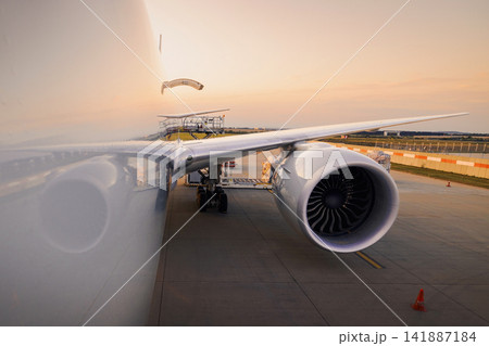 Reflection of wing and engine on cargo airplane fuselage during loading at sunset Reflection of wing and engine on cargo airplane fuselage during loading at sunset 141887184