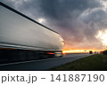Motion blurred truck driving fast on highway at sunset 141887190