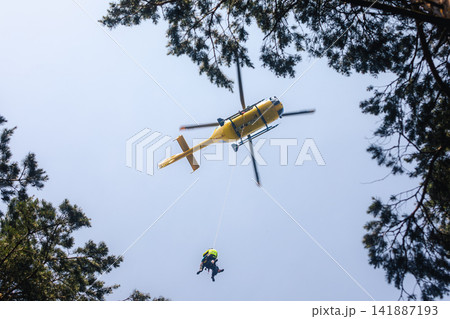 Rescuer on rope under a flying helicopter of emergency medical service Rescuer on rope under a flying helicopter of emergency medical service 141887193