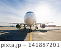 Front view of airplane taxiing toward airport runway on sunny day 141887201