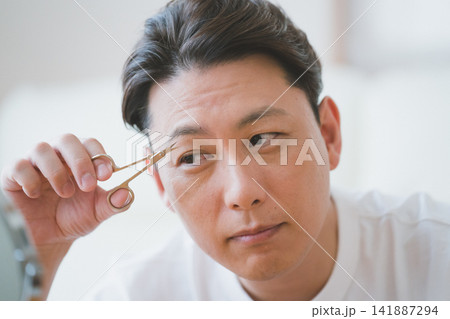 鏡の前で眉毛ハサミで眉毛を微笑みながら整えるミドル男性のメンズビューティー 鏡の前で眉毛ハサミで眉毛を微笑みながら整えるミドル男性のメンズビューティー 141887294