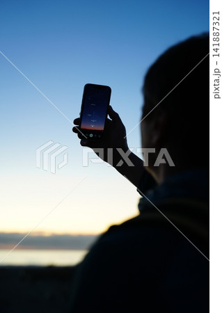 Person Holding Smartphone Against Evening Sky Person Holding Smartphone Against Evening Sky 141887321