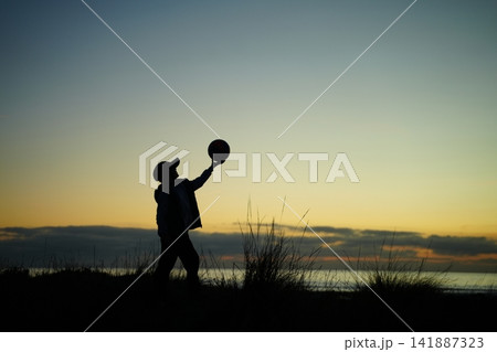 Silhouette of Child Balancing Ball at Sunset 141887323