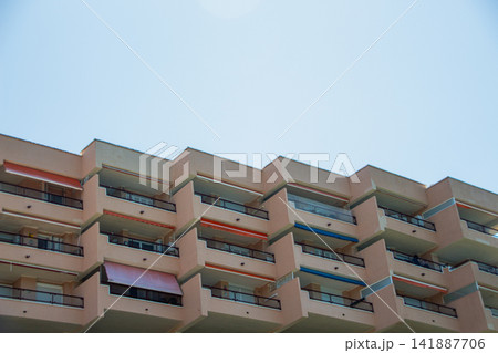 Residential building exterior with balconies against blue sky 141887706