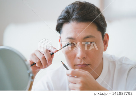 アイブロウブラシとペンシルで眉毛を丁寧に整えるミドル男性のメンズメイクアップ アイブロウブラシとペンシルで眉毛を丁寧に整えるミドル男性のメンズメイクアップ 141887792