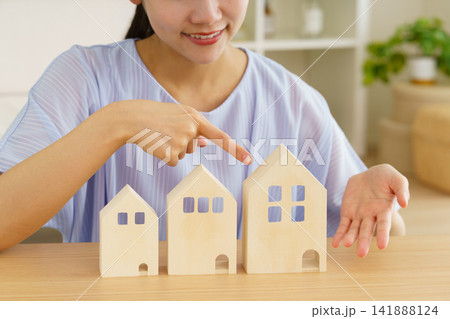テーブルの上の住宅の模型を指差す若い女性の手元 テーブルの上の住宅の模型を指差す若い女性の手元 141888124