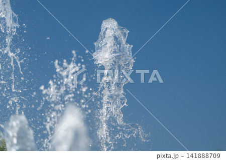 Dancing water jets create a mesmerizing display under a clear blue sky 141888709