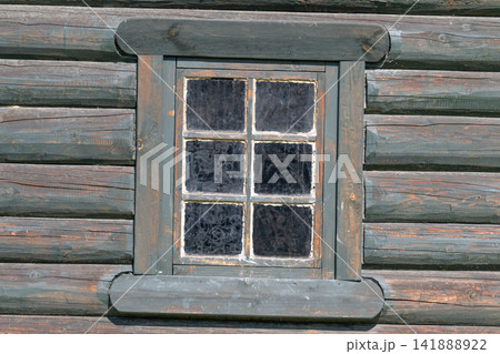 Charming wooden cabin window revealing rustic charm in a serene forest setting during daylight 141888922