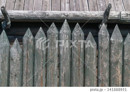 Wooden fence with pointed tops showcases rustic craftsmanship and structure in an outdoor setting under bright sunlight Wooden fence with pointed tops showcases rustic craftsmanship and structure in an outdoor setting under bright sunlight 141888931