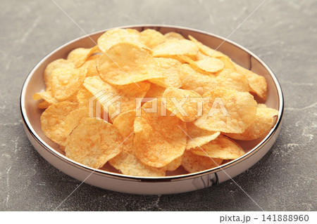 Potato chips on plate on grey concrete background. Potato chips on plate on grey concrete background. 141888960