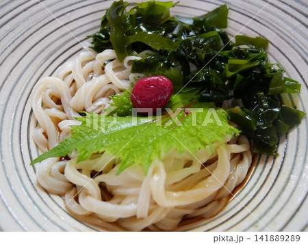 ガラス皿に盛られた冷やしうどんとわかめ・梅干し・大葉 141889289
