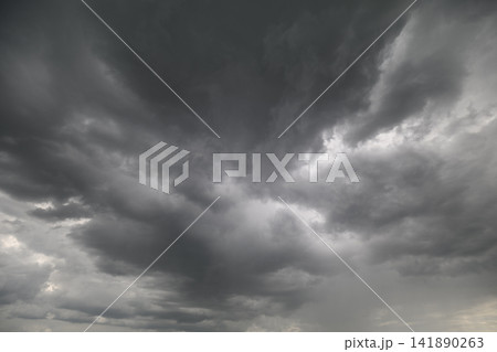 Dark clouds swirl ominously above hinting at an approaching storm during late afternoon in the sky 141890263