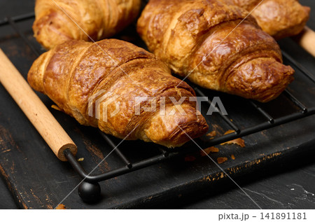 Freshly baked croissants on a black table, delicious breakfast Freshly baked croissants on a black table, delicious breakfast 141891181