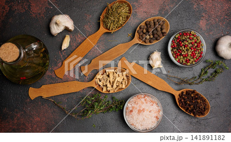 Various culinary spices in wooden spoons on brown background, top view 141891182