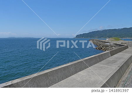 海へと続く長い堤防 鋸南町の海岸線から見渡す青い東京湾と緑広がる明鐘岬の景観 海へと続く長い堤防 鋸南町の海岸線から見渡す青い東京湾と緑広がる明鐘岬の景観 141891397