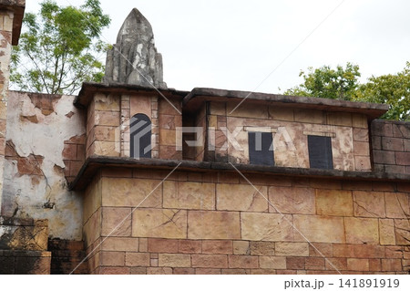 Ancient Stone Building Architecture with Weathered Walls and Green Foliage Ancient Stone Building Architecture with Weathered Walls and Green Foliage 141891919