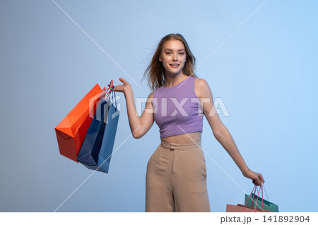 Woman holding many shopping bags, expressing happiness and joy after a rewarding retail therapy experience Woman holding many shopping bags, expressing happiness and joy after a rewarding retail therapy experience 141892904