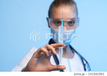 Healthcare worker holding a syringe, preparing for vaccination or injection, representing medical care and disease prevention 141892961