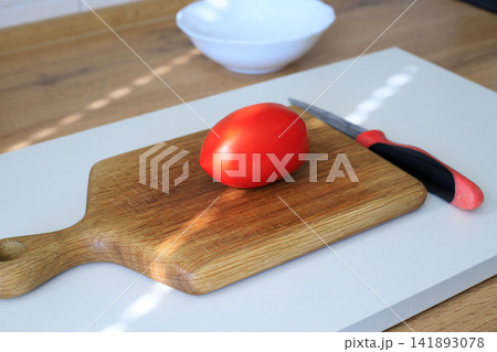 Red Tomato with Knife on Wooden Cutting Board for Culinary Food Preparation Red Tomato with Knife on Wooden Cutting Board for Culinary Food Preparation 141893078