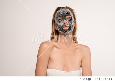 Young woman applying activated charcoal bubble foam mask on her face for a refreshing skincare treatment Young woman applying activated charcoal bubble foam mask on her face for a refreshing skincare treatment 141893234